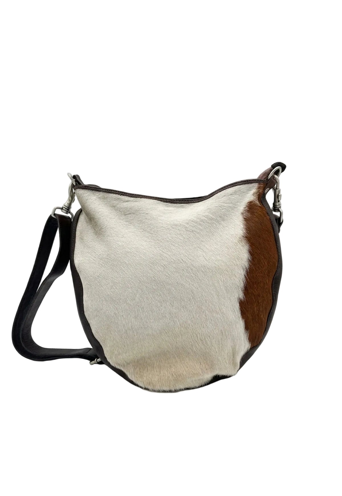 A cowhide shoulder bag with a brown and cream color-blocked pattern, black leather trim and strap, and silver-tone hardware, photographed on a white studio background.