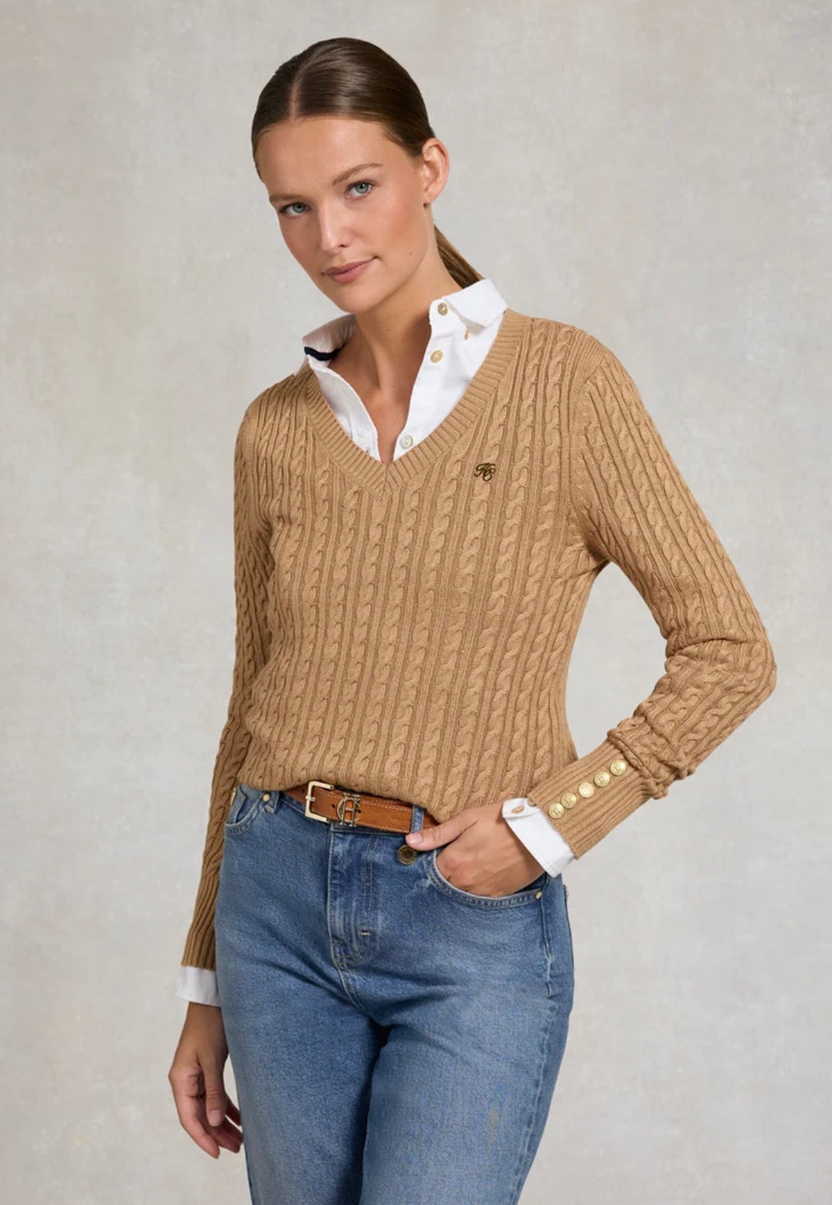 Holland Cooper Seattle V-Neck Knit in Dark Camel, featuring a cable-knit design, V-neckline, long sleeves and signature gold HC hardware at the shoulders and cuffs.